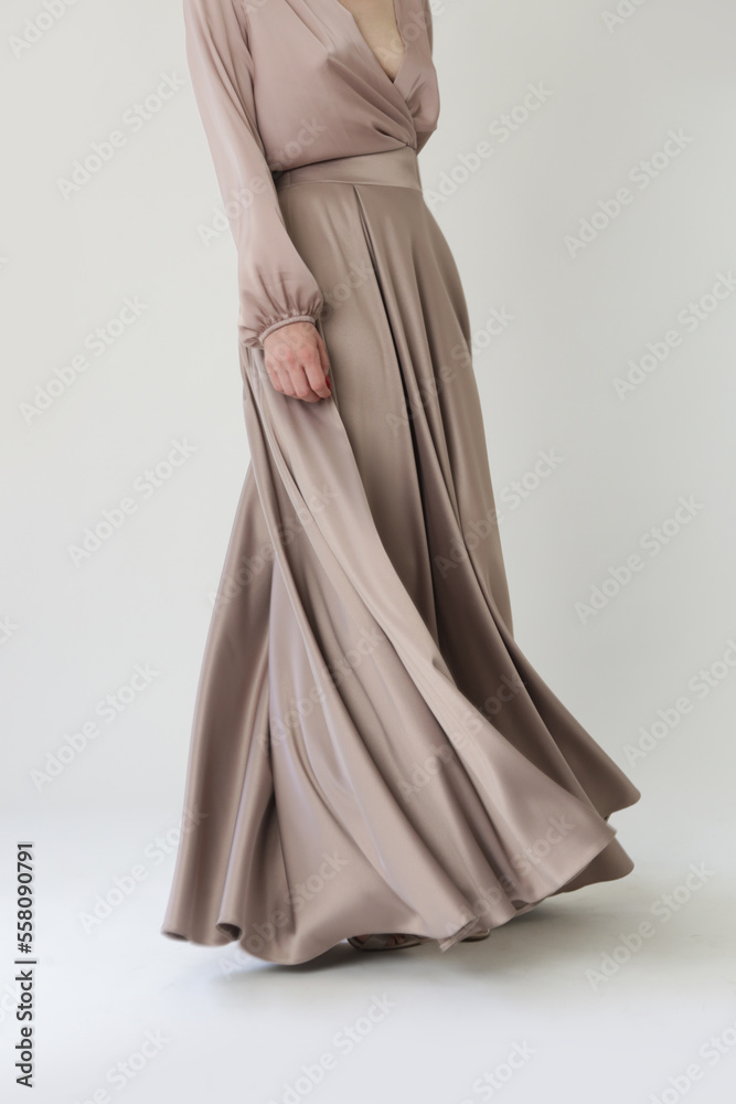 Studio shot of female fashion model in beige maxi circle skirt, Simplistic and elegant silk satin full length skirt