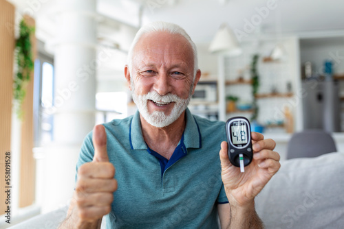 Blood sugar testing at home. Checking Blood Sugar Level At Home. Diabetic Checking Blood Sugar Levels. Senior man checking blood sugar level by glucometer and test stripe at home photo