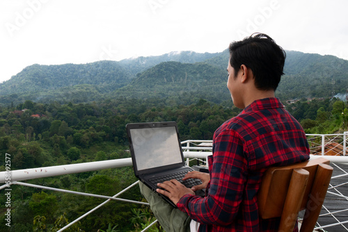 Asian man enjoys freelance work on her laptop on vacation. freelance or digital nomad concept