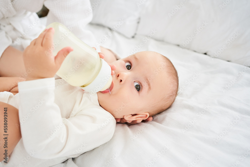 Cropped portrait of a smiling little toddler holding a bottle. Cropped portrait of a smiling little toddler holding a bottle.