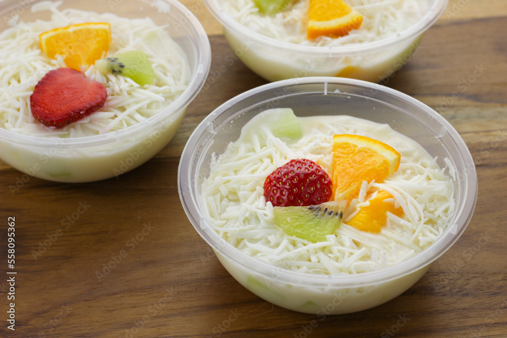 selective focus creamy fruit salad served in plastic bowl on wooden background selective focus creamy fruit salad served in plastic bowl on wooden background