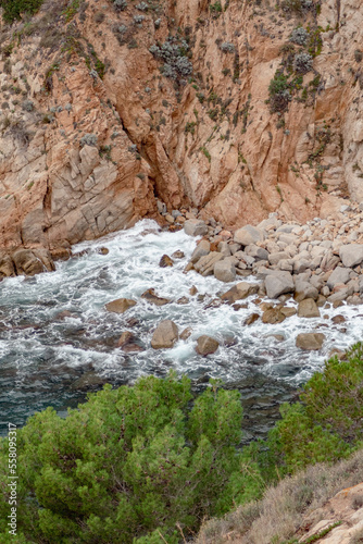 La espuma del mar Mediterráneo formándose al romper las olas contra las rocas de los acantilado de las murallas del pueblo catalan Tossa de Mar. photo