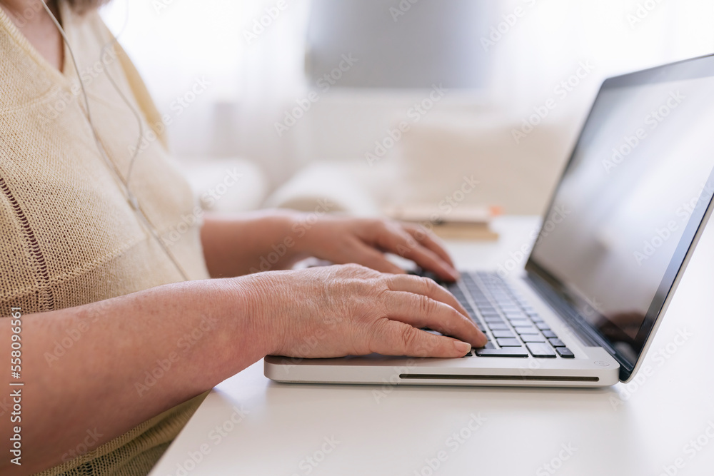 Cropped, close-up image, Retired middle aged woman using laptop computer, typing on keyboard, browsing internet at home. Cropped, close-up image, Retired middle aged woman using laptop computer, typing on keyboard, browsing internet at home.