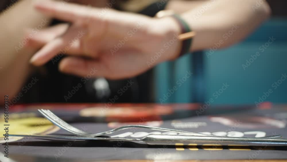 The girl in the Cafe. There are forks and a Knife on the table, she looks at her Watch and Waits for her Order. Close-up. The girl in the Cafe. There are forks and a Knife on the table, she looks at her Watch and Waits for her Order. Close-up.