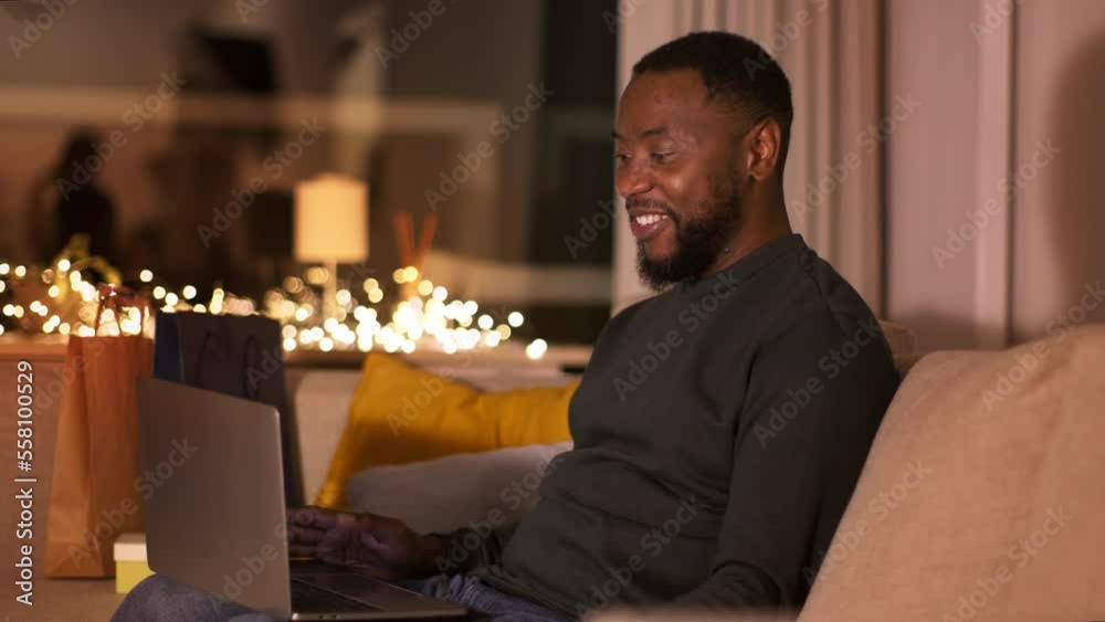 Online meeting. Young african american man video chatting with friends on laptop, sitting at home in evening, free space Online meeting. Young african american man video chatting with friends on laptop, sitting at home in evening, free space