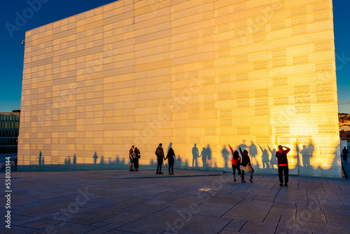 Tourists having fun with their shadows at the Oslo opera house at sunset