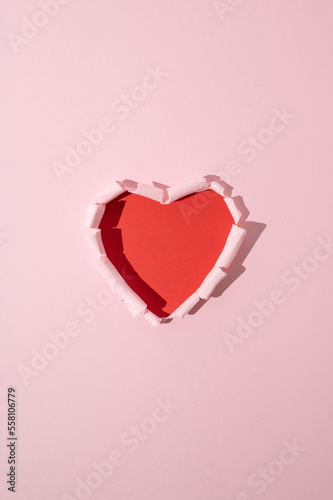 Red heart made of torn pink paper. Minimal love or valentine concept.