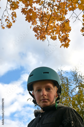 A boy in a protective helmet for riding a bicycle or scooter. Autumn. © dvoinik
