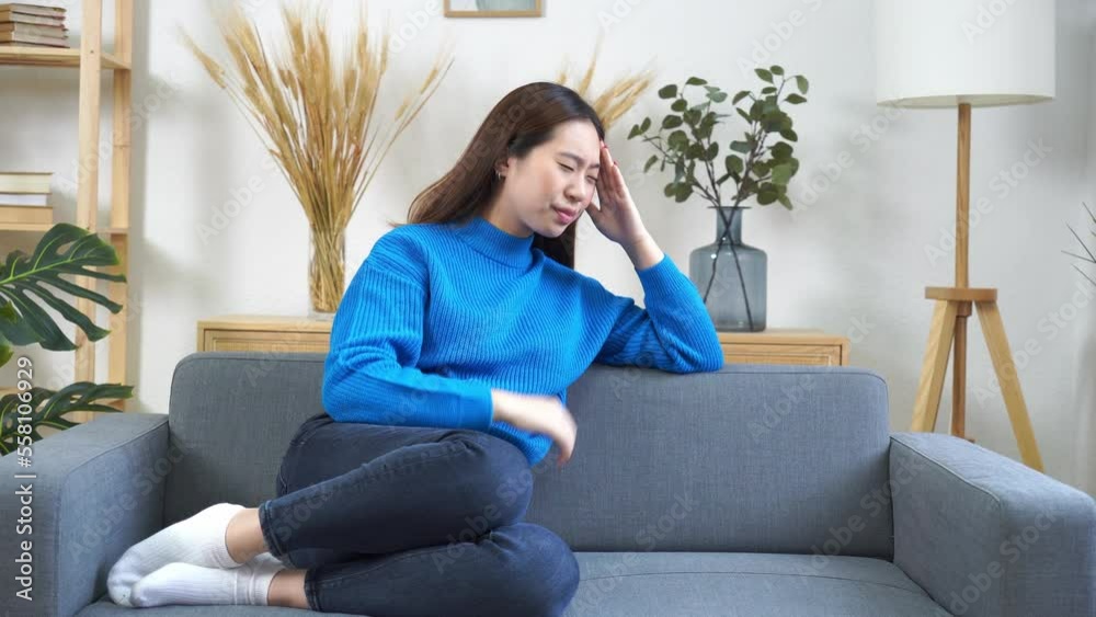 Full body of young female in casual clothes sitting on sofa and leaning on hand while resting in cozy living room Full body of young female in casual clothes sitting on sofa and leaning on hand while resting in cozy living room