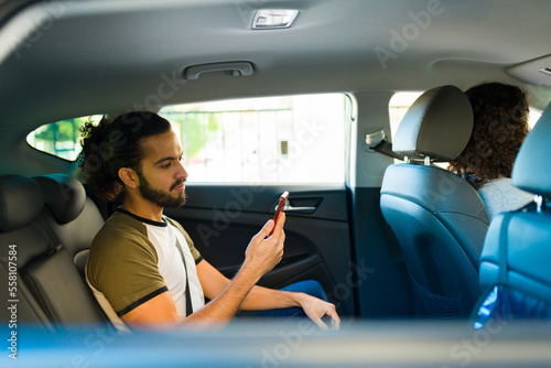 Attractive man texting and using the rideshare app © AntonioDiaz