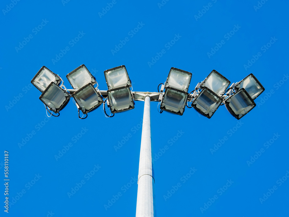 Sport area flood lights on a metal poll against blue cloudy sky. Sport area flood lights on a metal poll against blue cloudy sky.