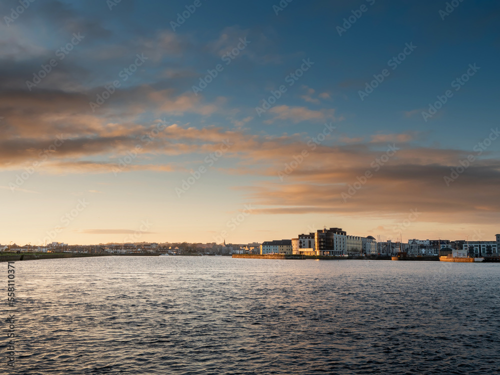 Sunset sky over river Corrib in Galway city, Ireland. High level of water. Calm nature scene. Irish landscape.