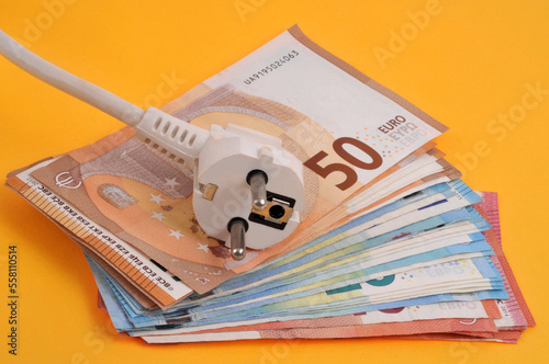 Concept de dépenses d'électricité avec une rallonge électrique sur une liasse de billets de banque isolé sur fond jaune photo