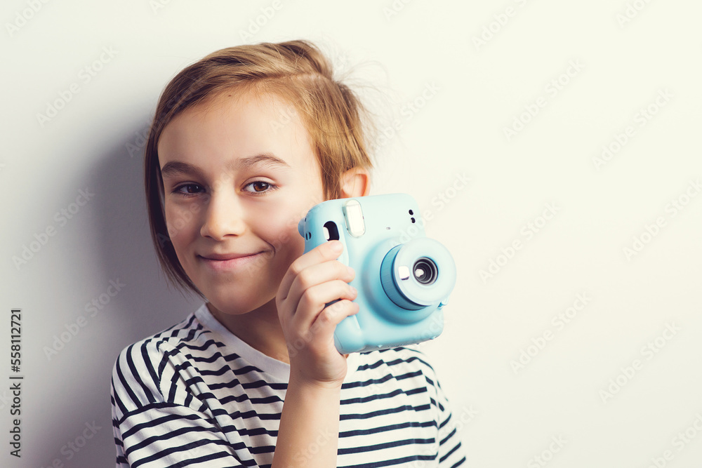 Cute boy holding photo camera. Stylish kid posing over grey background. Cute boy holding photo camera. Stylish kid posing over grey background.
