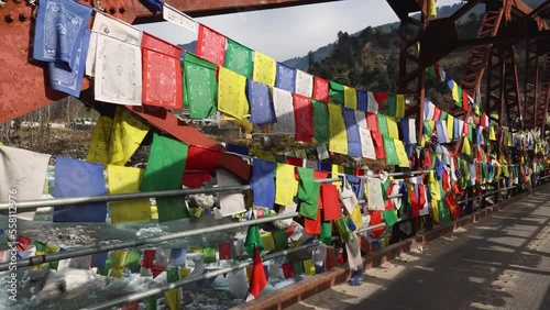 Kullu Manali Himachal Pradesh India. Buddhist prayer flags fluttering in the wind. Old Iron bridge over Beas river flowing through beautiful snow covered Indian mountain in Himalayas.  photo