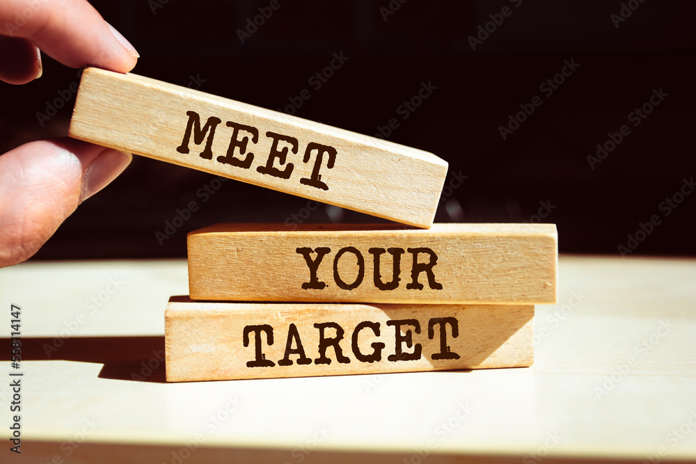Closeup on businessman holding a wooden blocks with text MEET YOUR TARGET, business concept Closeup on businessman holding a wooden blocks with text MEET YOUR TARGET, business concept