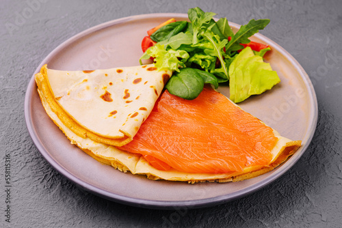 Pancake with red fish fillet on plate