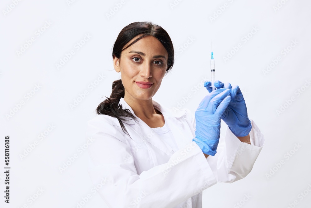 Woman doctor with syringe in hand in medical gown on white background nurse in blue gloves, covid-19 vaccine, shot for pain, concept of health and science Woman doctor with syringe in hand in medical gown on white background nurse in blue gloves, covid-19 vaccine, shot for pain, concept of health and science
