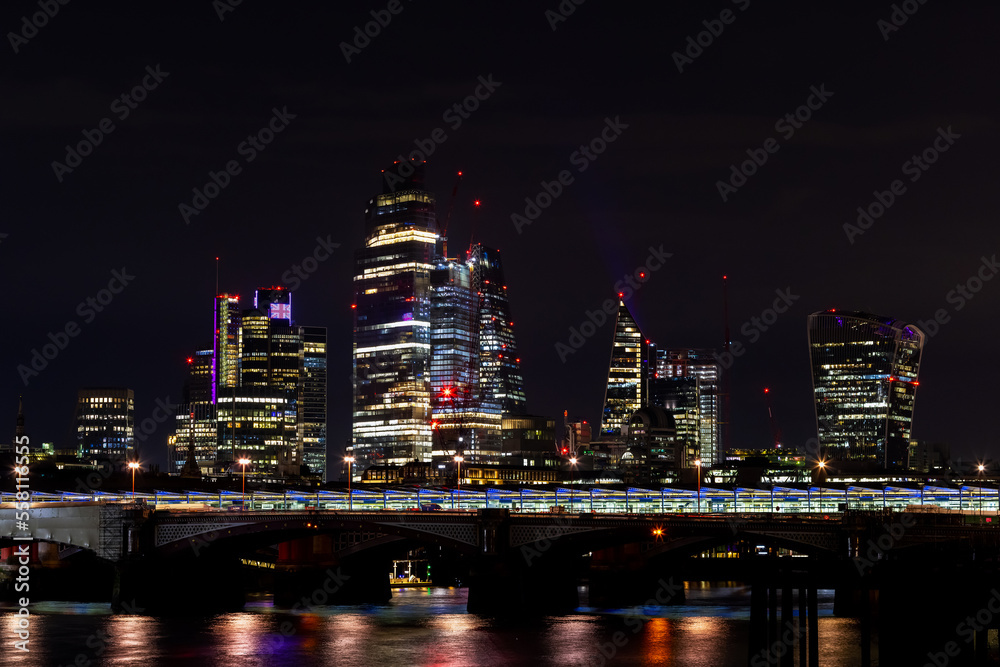 Beautiful view of London city landscape from Thames waterfront at night, handheld shot. Rapid growth and urban development concept.