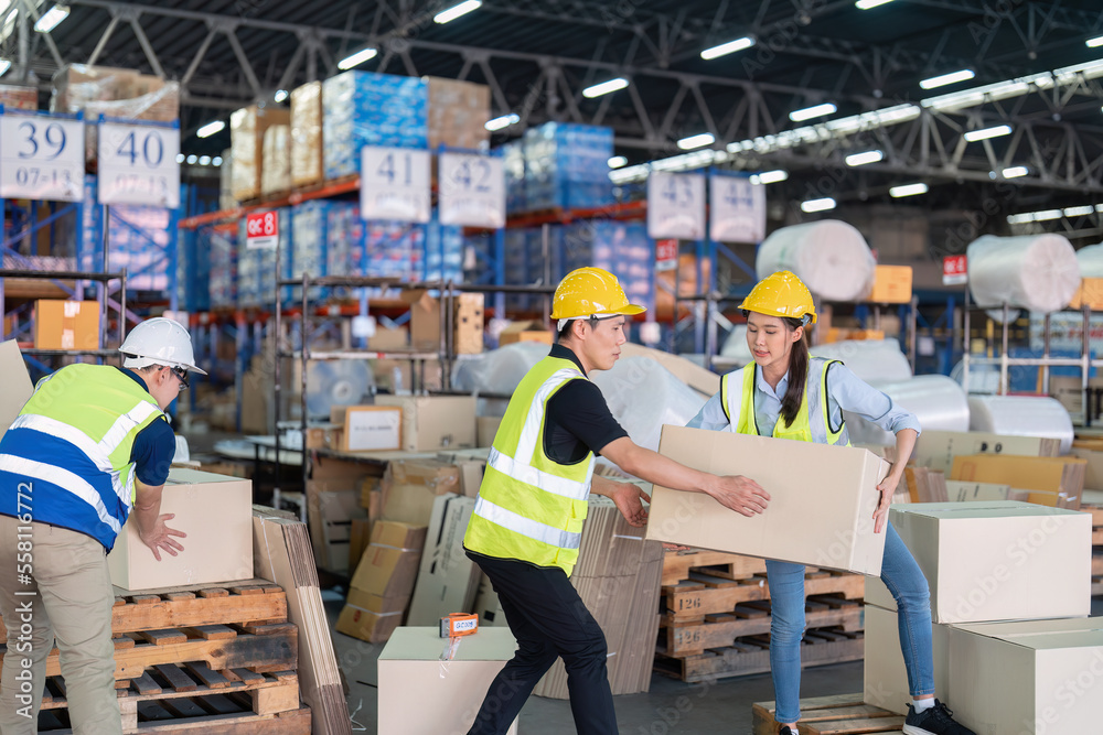 Staff in large storage warehouse together packing goods and carry carton box on pallet Staff in large storage warehouse together packing goods and carry carton box on pallet