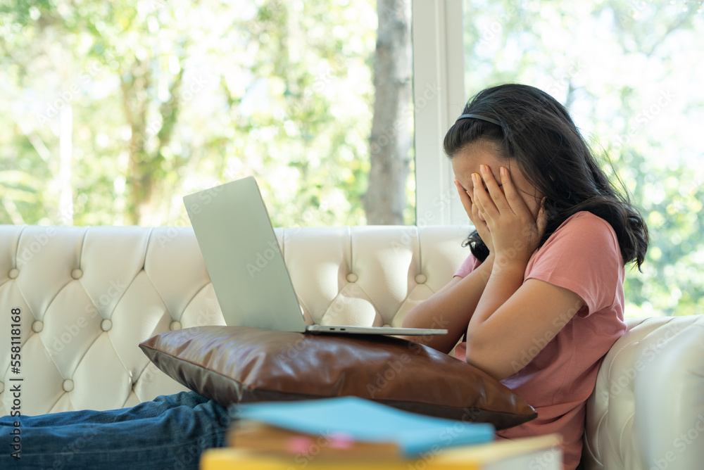 Tired schoolgirl studying online on laptop at home, Teen female student exhausted from looking at screen, doing assignments or communicating on web. teenage female student preparing for exams at home