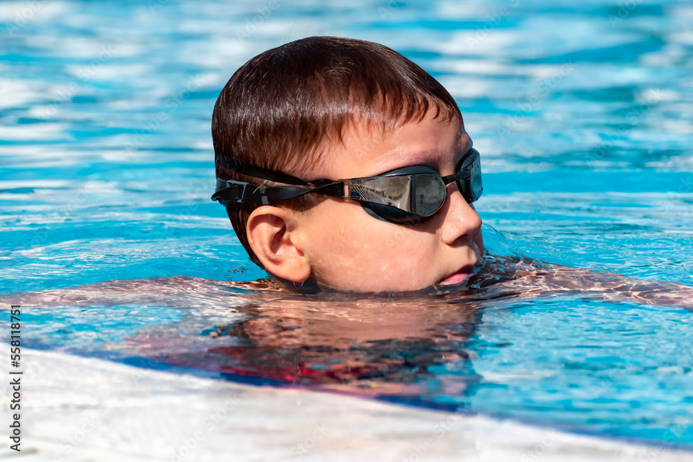 Boy child swimmer in swimming pool. Water sports, training, competition, summer activities, healthy lifestyle, children's sport