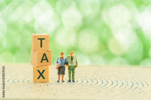 Retirement, pension income tax and social security benefit concept : Older couple stands close to wood cubes with the word TAX on a maze. Depicting tax relief on pension contributions for high earners photo