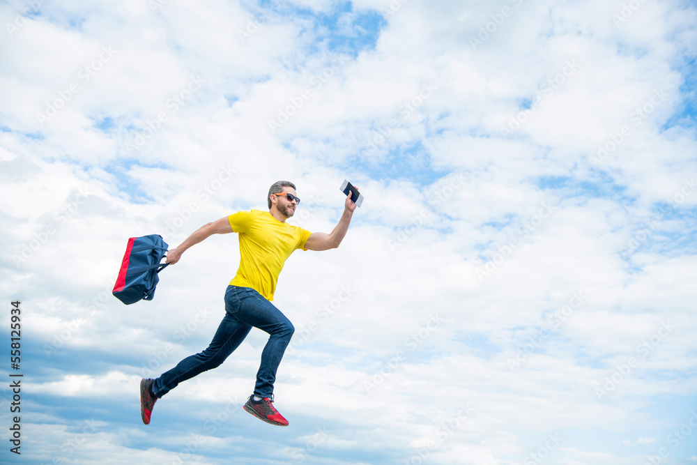 Energetic guy running with travel bag midair sky background, copy space Energetic guy running with travel bag midair sky background, copy space