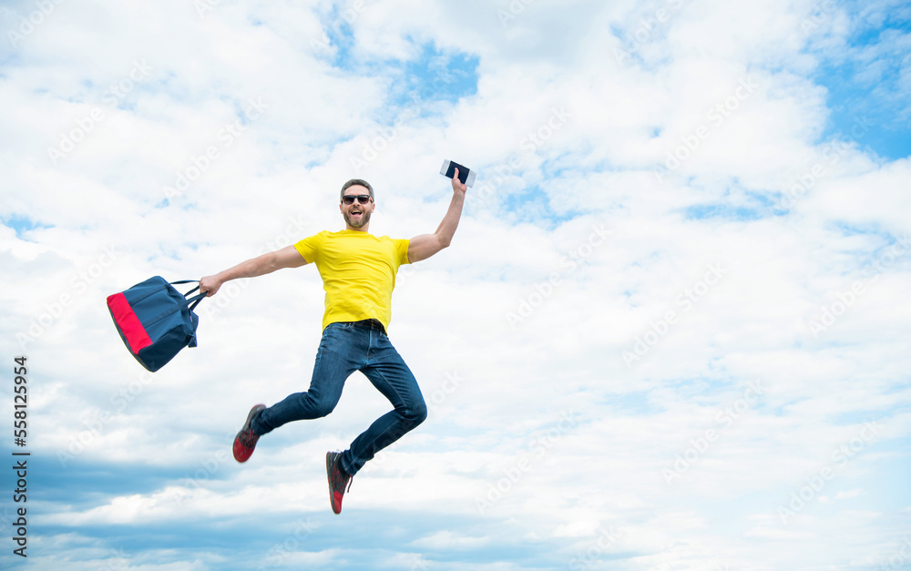 Active guy jumping with travel bag midair sky background, copy space Active guy jumping with travel bag midair sky background, copy space
