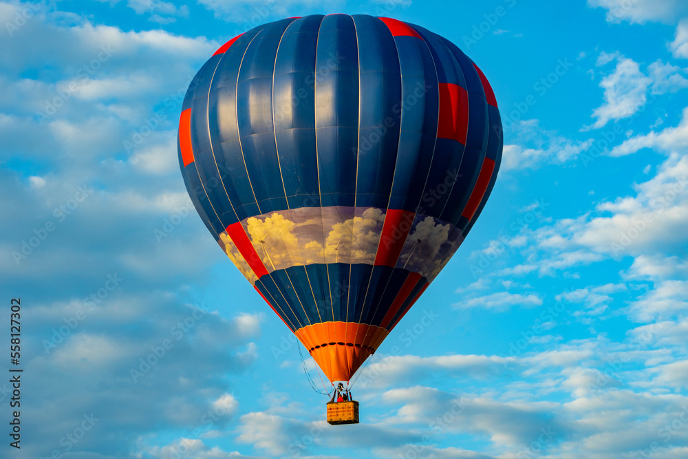 Fototapeta premium blue bright hot air balloon flies against the blue sky in the clouds