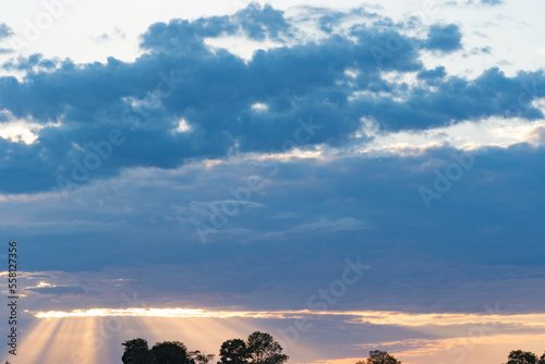 rays of the setting sun break through the dramatic sky in thick rain clouds