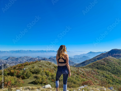 Woman on top of Goli Vrh with scenic aerial view on dramatic mountain chains of Dinaric Alps surrounding Lake Skadar National Park, Montenegro, Balkan, Europe. Valley covered by mystical fog. Freedom