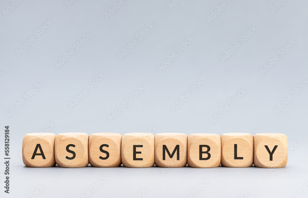 Assembly word on wooden blocks on gray background. Copy space Assembly word on wooden blocks on gray background. Copy space