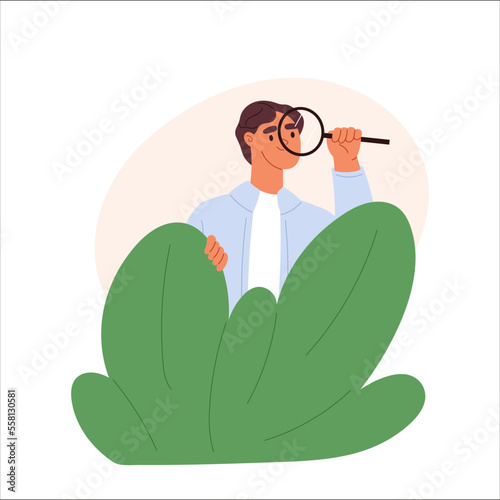 Young man spying, observing, sneaking. Guy with magnifying glass peeping, hide behind shrubs
