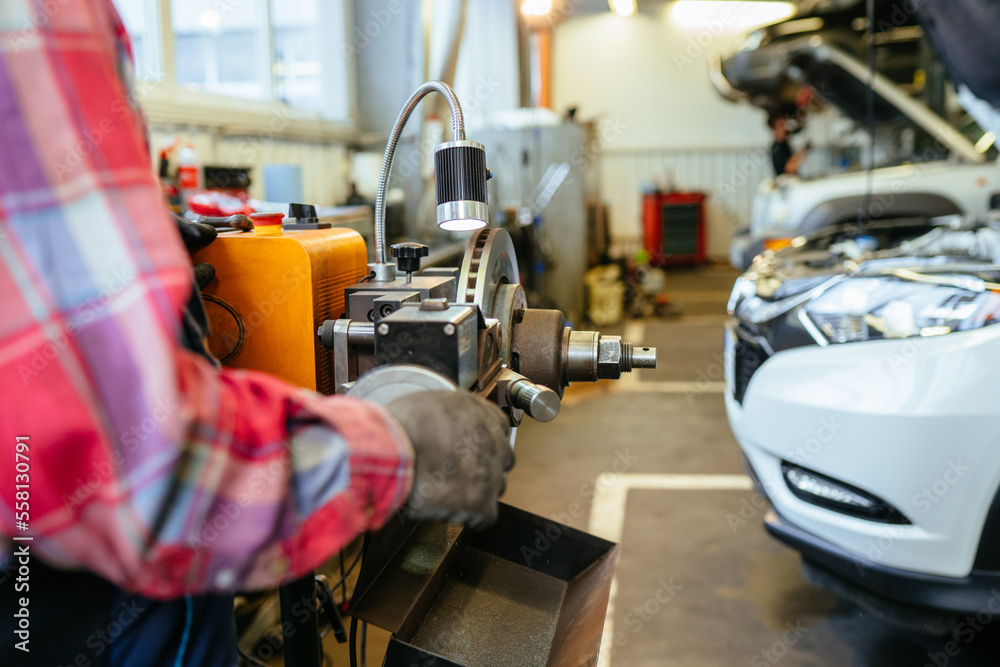 Fototapeta premium Special equipment automobile brake disk replacement in car repair shop or garage. Mechanic checking car wheel rim.