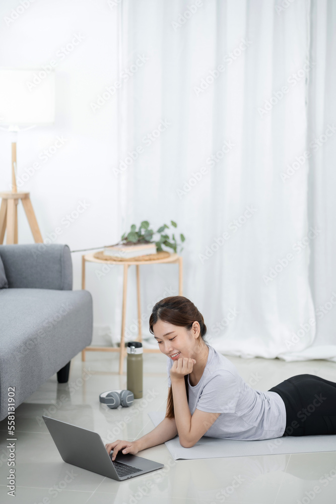 Young asian woman attractive exercises workout at home and watching Online sports tutorials over laptop Young asian woman attractive exercises workout at home and watching Online sports tutorials over laptop