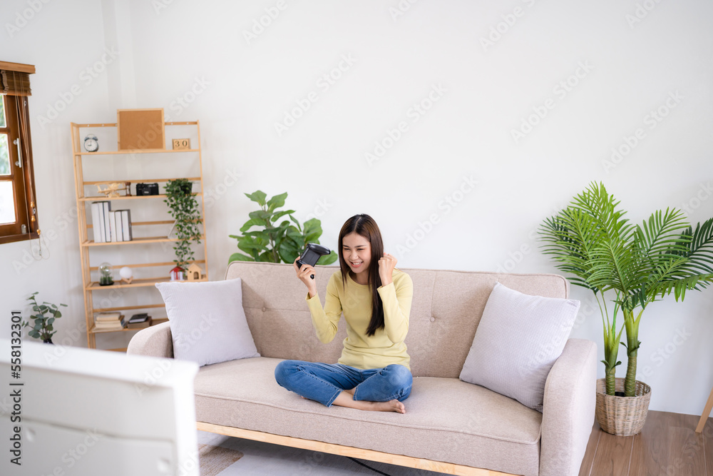 Asian Woman playing video games at home. .Cheerful gamer playing online games with console Asian Woman playing video games at home. .Cheerful gamer playing online games with console