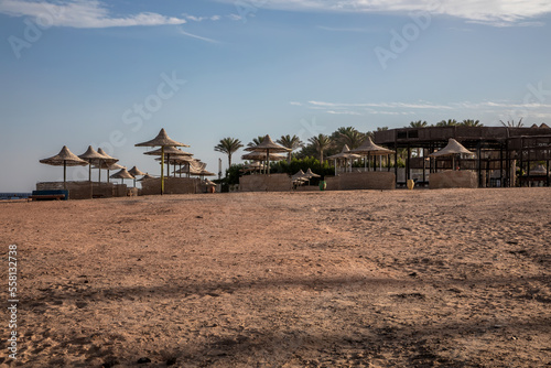 Beautiful abandoned beach. Umbrellas and sunbeds on the beach. Sunny summer day. Beautiful abandoned beach.