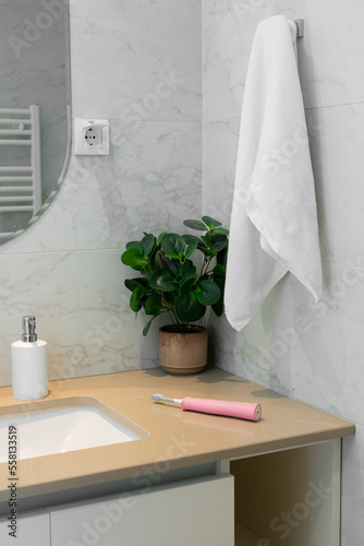 Bath interior, white towel and pink electric toothbrush 