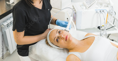 High angle shot of a woman laying down with her eyes open and receiving microdermabrasion treatment. Beauty concept. High quality photo