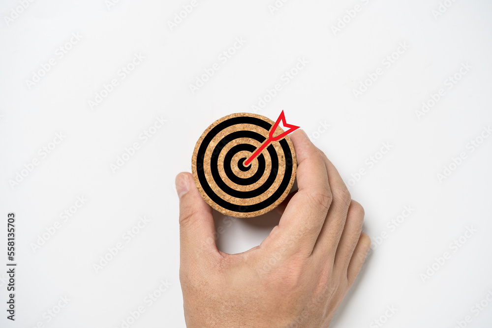 Hand holding dartboard with arrow which print screen on round wooden for setup business objective goal and target concept. Hand holding dartboard with arrow which print screen on round wooden for setup business objective goal and target concept.