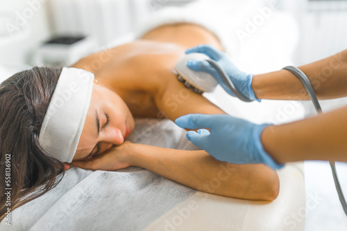 Medium shot of a woman laying down in a towel with her eyes closed and receiving anti-cellulite massage treatment. Beauty concept. Spa concept. High quality photo