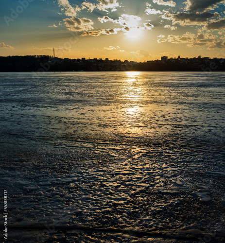 reflection of the sunset in the frozen cracked ice in the thaw, the silhouett...