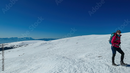 Woman hiking in snow covered landscape near Ladinger Spitz, Saualpe, Lavanttal Alps, Carinthia, Austria, Europe. Trekking in Austrian Alps in winter on a sunny day. Ski touring and snow shoe tourism
