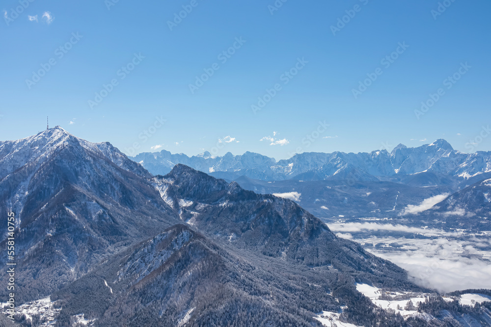 Scenic view of snow capped mountain peak Dobratsch, Julian Alps and the Karawanks (Karawanken) seen from Kobesnock in Bad Bleiberg, Carinthia, Austria, Europe. Winter wonderland landscape on sunny day