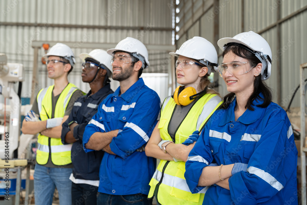 Group of robotic engineers wear helmets safety standing and arms crossed at factory workshop. Technician professional team robot arm welding machine. Group of robotic engineers wear helmets safety standing and arms crossed at factory workshop. Technician professional team robot arm welding machine.