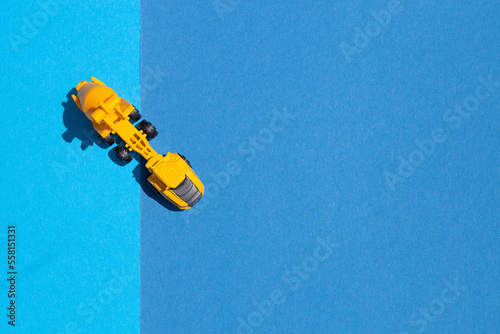 Top view of a yellow toy concrete mixer on a blue background. Construction equipment.
