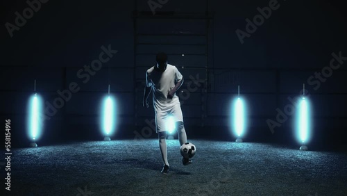 african athlete playing football alone at night, portrait of man practicing keepie uppie exercise photo