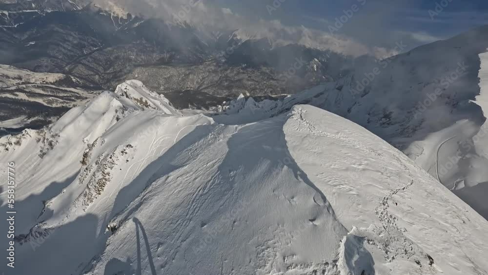 Mountain sunny landscape stone ridge slope cinematic ski resort alpine environment aerial view. Mountaineering scenery dive from top snow picturesque rocky valley ropeway travel tourism FPV drone shot
