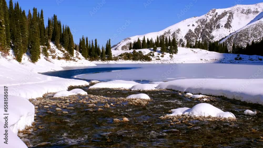 Transparent clean water of a mountain river flows into the lake in the winter season Transparent clean water of a mountain river flows into the lake in the winter season